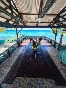 a wooden table with chairs and the ocean in the background at Motu Tahuhu Lodge in Rangiroa