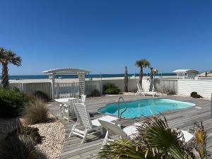 a deck with chairs and a swimming pool and the beach at Captain's Choice in Atlantic Beach