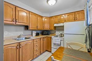 a kitchen with wooden cabinets and a white refrigerator at Modern Manor Studio WiFi Parking in St. John's