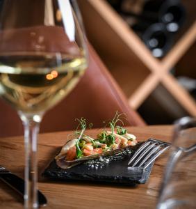 un plato de comida y una copa de vino en Domaine de Suzel Hôtel & Spa, en Vignieu