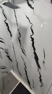 Una ducha blanca con piedras negras en la pared. en Hospedaje en Valencia Tipo Estudio, en Valencia