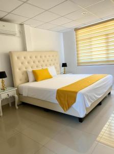 Un dormitorio con una cama grande con una almohada amarilla. en The Royalty Lite, en Guayaquil