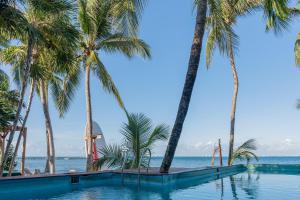a swimming pool with palm trees and the ocean at Mayan Monkey Isla Mujeres - Social Hotel in Isla Mujeres