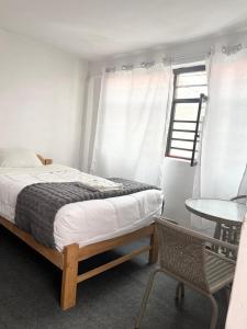 ein Schlafzimmer mit einem Bett, einem Tisch und einem Fenster in der Unterkunft ENEDE HOSTEL in Cusco
