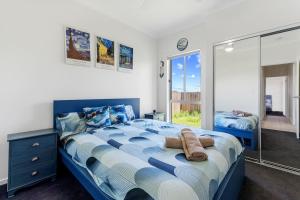 a bedroom with a blue and white bed and a mirror at Comfy Home in Deebing Heights in Loamside
