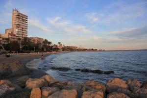 a beach with rocks in the water and a building at Xaloc Habitaciones in Santa Pola