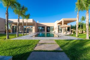 a house with a swimming pool and palm trees at Berber Garden in Aït Amara