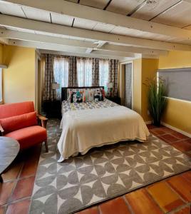 a bedroom with a large bed and a red chair at Mid-century marvelous 1 bed, pets welcome in Las Cruces