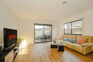 Melton SouthにあるOpen Plan Comfort Sunny Living BBQ in Backyardのソファとテレビのあるリビングルーム