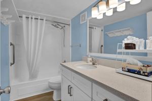 a bathroom with a sink and a toilet and a mirror at Summer Sands - 401 by Sea Scape Properties in Wrightsville Beach