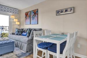 a living room with a table and chairs and a couch at Summer Sands - 401 by Sea Scape Properties in Wrightsville Beach