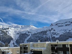 un edificio con una montaña cubierta de nieve en el fondo en Studio neuf pour 4 pers. au centre de Flaine avec balcon - FR-1-425-170, en Flaine