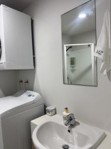 a white bathroom with a sink and a mirror at Charming & Cozy Apartment in the Heart of Auckland - 2 bd-2 bth-free carpark in Auckland +28 photos