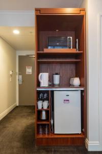 a kitchen with a refrigerator and a microwave on a shelf at Chic Hotel Room at City Life Auckland in Auckland