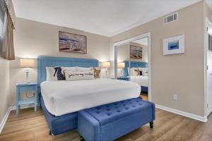 a bedroom with a large bed and a blue stool at Summer Sands - 401 by Sea Scape Properties in Wrightsville Beach +7 photos