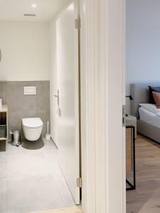 a white bathroom with a toilet and a bed at Hotel Murten in Murten