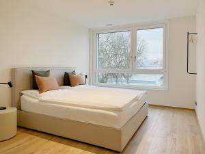 a white bedroom with a large bed and a window at Hotel Murten in Murten