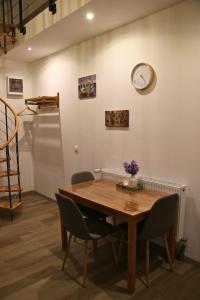 a dining room table with chairs and a clock on the wall at Ferienwohnung Am Sieler in Südbrookmerland +9 photos