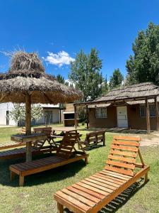 a group of tables and chairs with a hut at Complejo de Cabaña con pileta CABLE A TIERRA Cabaña Blend in San Rafael +9 photos