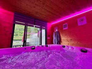 a purple bathroom with a tub with pink lighting at Le Hourmigué maison 130m2 avec jacuzzi à 15mn de Luchon in Cierp
