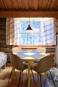 Una mesa y sillas en una habitación con ventana. en Ski-inn kelohuoneisto Pyhätunturissa, en Pelkosenniemi