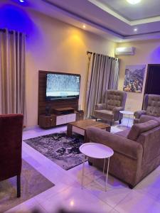 Una sala de estar con un sofá y un televisor de pantalla plana. en The Private Pearl Apartment, en Ikeja