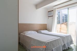 twee bedden in een kamer met een groot raam bij Apartamento em Macae Proximo a Praia do Farol in Imbetiba