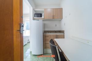 een kleine keuken met een witte koelkast en een tafel bij Apartamento em Macae Proximo a Praia do Farol in Imbetiba