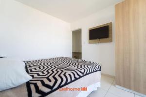 ein Schlafzimmer mit einem schwarz-weißen Bett und einem Fernseher in der Unterkunft Apto no Centro de Macae a 550m da Praia do Farol in Imbetiba