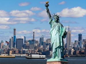 a statue of liberty with a city in the background at Spacious & Stylish 2BR Apartment Near Manhattan in Jersey City