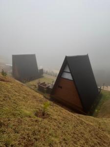 a couple of tents on a hill with fog at Cabana Veneza in Santa Teresa