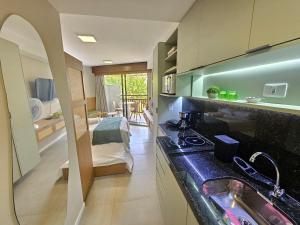 a kitchen with a sink and a room with a bed at Atlântico Carneiros - Pé na areia no melhor trecho da Praia dos Carneiros in Praia dos Carneiros