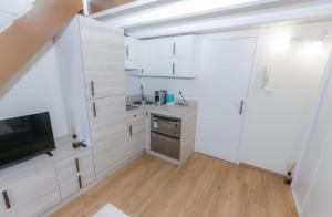 a kitchen with white cabinets and a flat screen tv at Loft Moderne - À Deux Pas de Monte-Carlo in Roquebrune-Cap-Martin