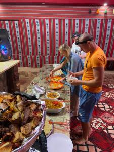 a group of people standing around a table with food at Desert Time in Wadi Rum