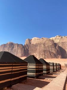 a row of tents in the desert near a mountain at Desert Time in Wadi Rum