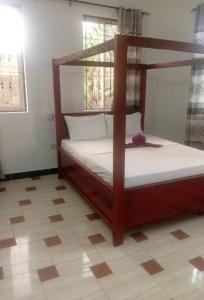 a bedroom with a canopy bed with white sheets at Kijani House in Banda Kuu +12 photos