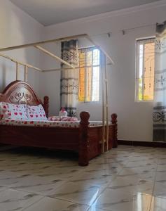 a bedroom with a wooden bed in a room with windows at Kijani House in Banda Kuu