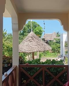 a view from the porch of a resort with a straw umbrella at Kijani House in Banda Kuu