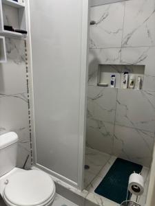 a white bathroom with a shower and a toilet at Alojamiento en Ayangue in Santa Elena