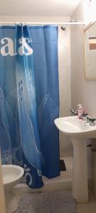 ein Badezimmer mit einem blauen Duschvorhang neben einem Waschbecken in der Unterkunft Complejo "El Padrino" in Villa Carlos Paz