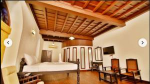 a bedroom with a bed and a tv and chairs at Boho Heritage in Kochi in Cochin