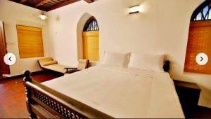 a bedroom with a large white bed and two windows at Boho Heritage in Kochi in Cochin +29 photos