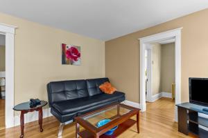 een woonkamer met een zwarte leren bank en een tafel bij Midstream Executive 2BR Wi-Fi Parking in St. John's