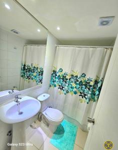 uma casa de banho com um lavatório, um WC e uma cortina de chuveiro. em Parque Mar Depto em El Tabo