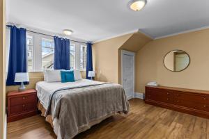 een slaapkamer met een bed met blauwe gordijnen en een spiegel bij Midstream Executive 2BR Wi-Fi Parking in St. John's
