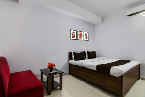 een slaapkamer met een bed en een rode stoel bij Hotel O Deendayal Crossway Ranchi Formerly Yashoda in Rānchī