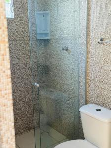 a bathroom with a glass shower with a toilet at Fonte dos Corais - Suíte Onda do Mar in Maragogi