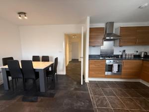 a kitchen with a table and black chairs in a room at Modern flat in Abbey Wood in Abbey Wood