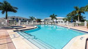 ein großer Swimmingpool mit Stühlen und Palmen in der Unterkunft San Marco Villa - SMV62 in Marco Island