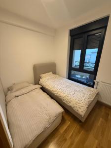 two beds in a room with a window at Una Lux Apartment in Sombor